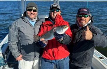 Three anglers on boat displaying speckled trout catch on Florida's Nature Coast